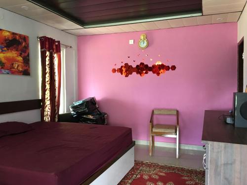 a room with a pink wall with a bed and a chair at LaCliff Nature Home in Dhanaulti