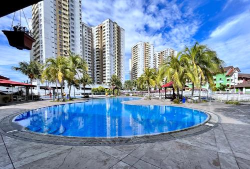 a swimming pool with palm trees and buildings at Naura Homestay Selangor Kuala Lumpur in Batu Caves