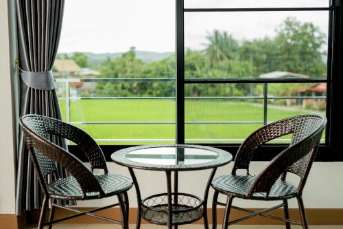 a glass table and two chairs in front of a window at Baan chomphu @Pua in Pua