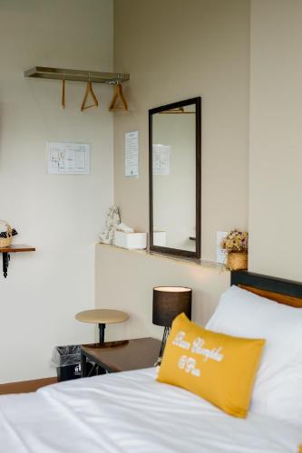 a bed with a yellow pillow and a mirror at Baan chomphu @Pua in Pua