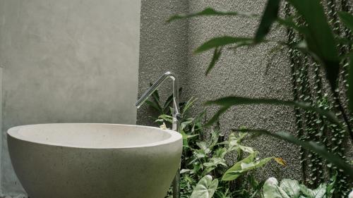 a bath tub sitting next to a wall with a plant at Annora Villas Seminyak in Seminyak