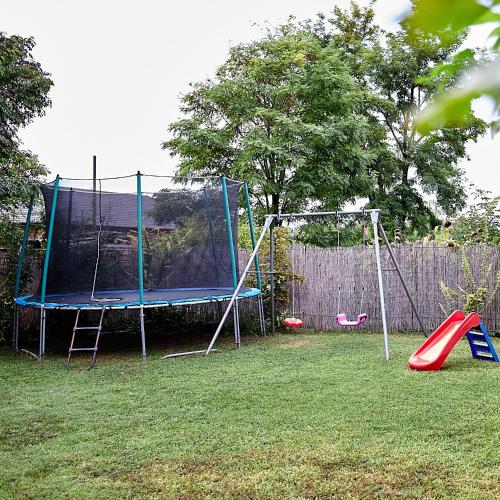 a playground with a trampoline in a yard at Klaudia Vendégház in Mórahalom