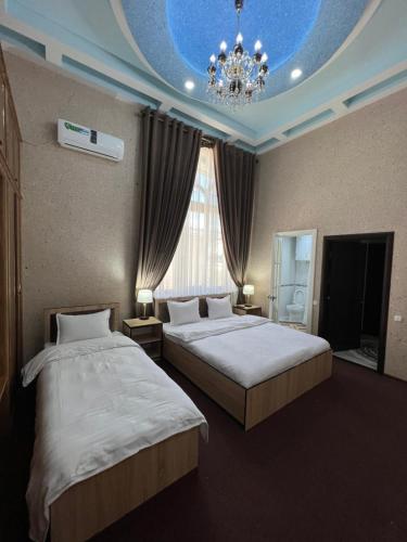 a hotel room with two beds and a chandelier at HOTEL DaMir in Samarkand
