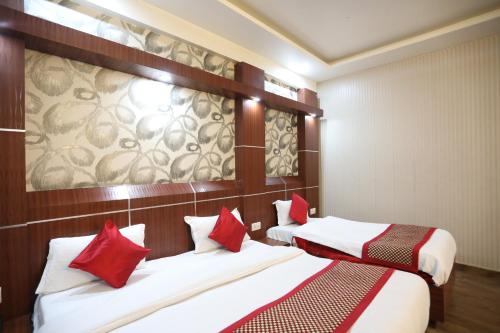 zwei Betten in einem Hotelzimmer mit roten Kissen in der Unterkunft HOTEL JAGDISH RESIDENCY in Katra
