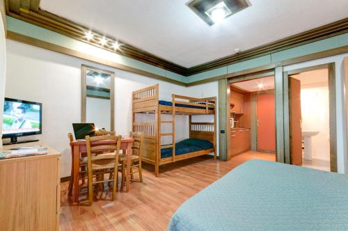 a bedroom with bunk beds and a desk and a table at Hotel Residence Club Primula in Pescasseroli