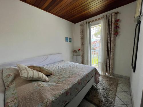 a small bedroom with a bed with a window at Casa verde no centro de Paraty in Paraty