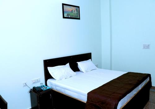 1 dormitorio con 1 cama grande con sábanas blancas en ASHOKA PALACE, en Sawāi Mādhopur
