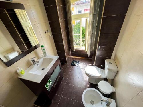 bagno con due servizi igienici, lavandino e finestra di Sweet Love Family Budget a Coimbra
