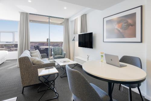 a hotel room with a table with a laptop on it at Meriton Suites Zetland in Sydney