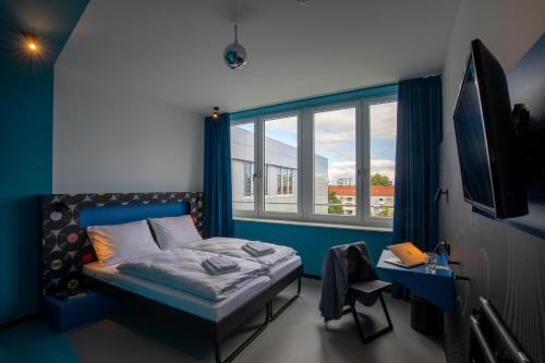 ein Schlafzimmer mit einem Bett und einem großen Fenster in der Unterkunft MEININGER Hotel Dresden Zentrum in Dresden