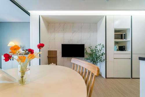 a dining room with a table with flowers in a vase at Urbanstay Jeju Airport in Jeju