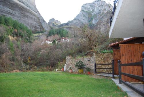 a house with a yard with a fence and mountains at Pyrgos Adrachti in Kalabaka
