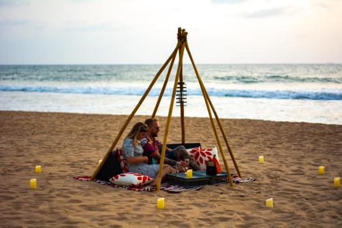 a family sitting in a swing on the beach at The Villa Bentota by KK Collection in Bentota