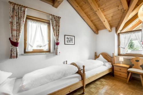 ラ・ヴィッラにあるresidence Manuelaの木製天井と窓が備わるドミトリールームのベッド2台分です。