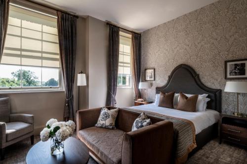 a bedroom with a bed and a couch and a chair at Stanbrook Abbey Hotel, Worcester in Worcester