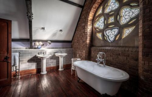 a bathroom with a tub and two sinks and a window at Stanbrook Abbey Hotel, Worcester in Worcester