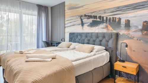 ein Schlafzimmer mit einem großen Bett und einem Gemälde an der Wand in der Unterkunft Prywatne apartamenty Sun & Snow w Porta Mare Marina z basenem in Dziwnów