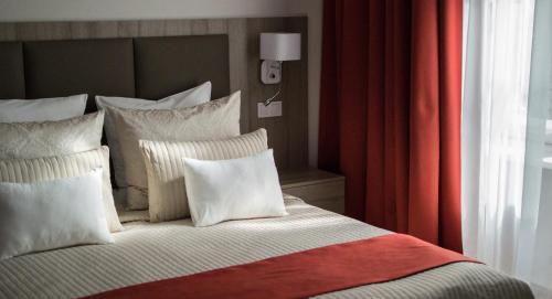 a bed with white pillows and a red curtain at Harmonia Palace - Luxury Apartments in Budapest