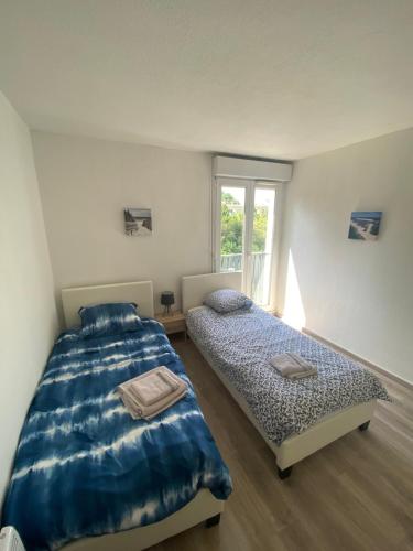 une chambre avec deux lits et une fenêtre dans l'établissement Appartement 3p, 72m2, centre ville, parking privé tout confort, à Biscarrosse
