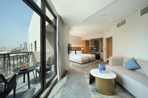 Arabian Park Dubai, an Edge by Rotana Hotel في دبي: غرفة معيشة مع أريكة وغرفة نوم