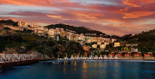 a river with a group of white chairs and buildings at Sirene Luxury Hotel Bodrum in Yalıkavak