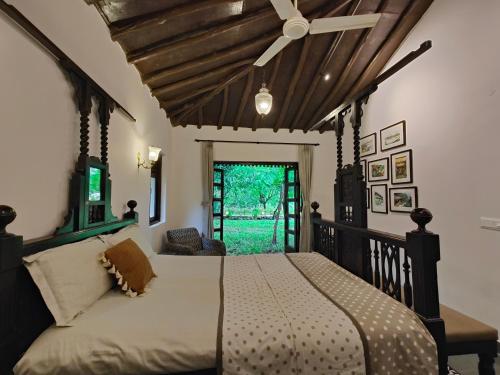 a bedroom with a bed with a ceiling fan at SaffronStays Mango Huts by the River, Pali in Jambhulpāda