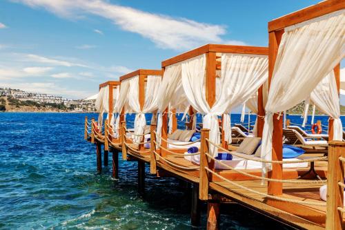 a row of chairs on a dock in the water at Sirene Luxury Hotel Bodrum in Yalıkavak