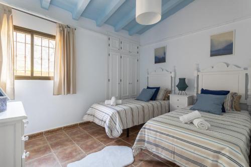 2 camas en una habitación con paredes blancas y techos azules en Villa Damian, en Málaga