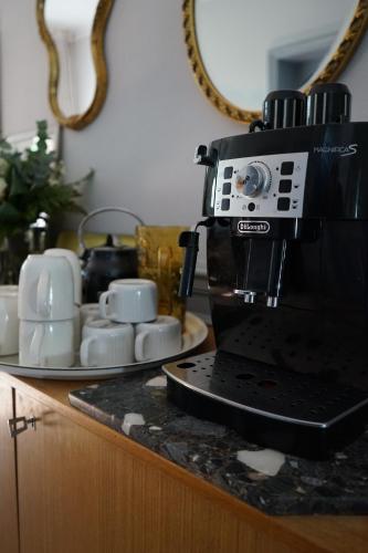 uma cafeteira preta sentada num balcão com chávenas em La Villégiature em Coutances