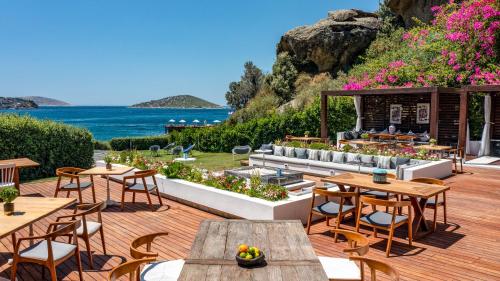 an outdoor patio with tables and chairs and the ocean at Sirene Luxury Hotel Bodrum in Yalıkavak