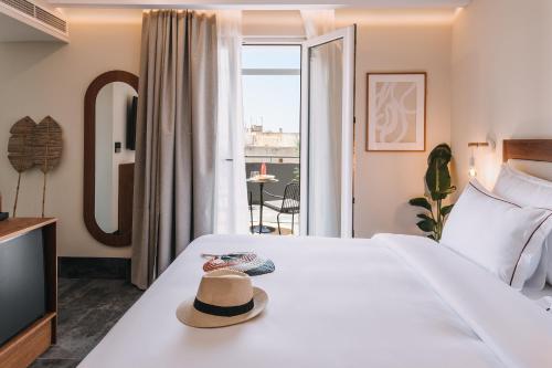 een hotelkamer met een bed met een hoed erop bij Dave by the Beach Loutraki, a member of Brown Hotels in Loutraki