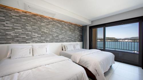 two beds in a room with a brick wall at Carib Condo Hotel in Tongyeong