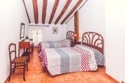 a bedroom with two beds and a table and a desk at Las Casicas del Tío Ángel-A in Los Alejos