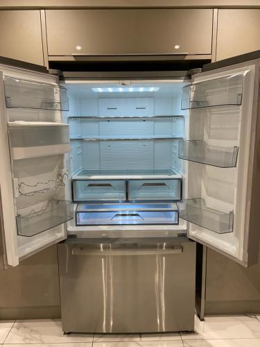 an empty refrigerator with its doors open in a kitchen at Boho Beach House - Beach location in Bournemouth