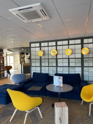 a living room with a blue couch and yellow chairs at Campanile Montpellier Ouest - Croix D'Argent in Montpellier