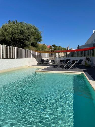 - une piscine avec des chaises et de l'eau bleue dans l'établissement Campanile Montpellier Ouest - Croix D'Argent, à Montpellier