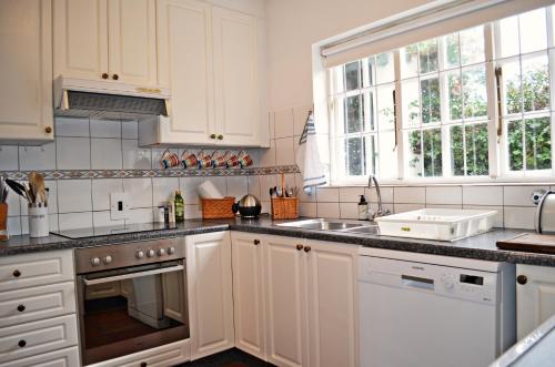 a kitchen with white cabinets and a sink at Bougainvillea House - The Heart of Simonstown in Simonʼs Town