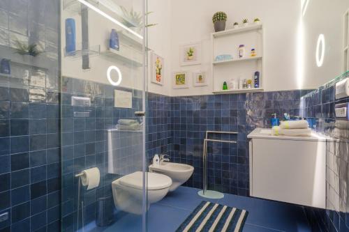a blue tiled bathroom with a toilet and a glass shower at Appartamento Soleluna in San Cataldo