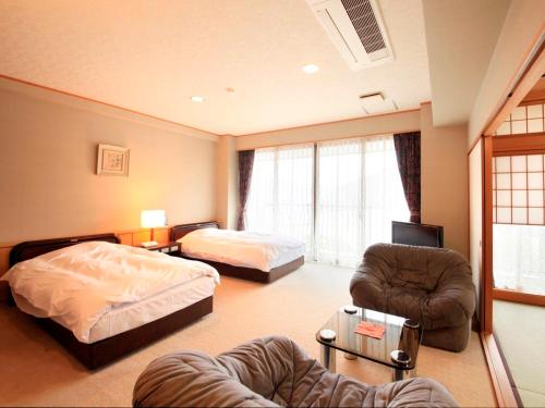a room with two beds and a bed and a couch at Hotel Kamogawaso in Takekara