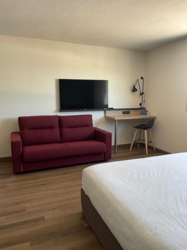 a hotel room with a red couch and a tv at Campanile Montpellier Ouest - Croix D'Argent in Montpellier