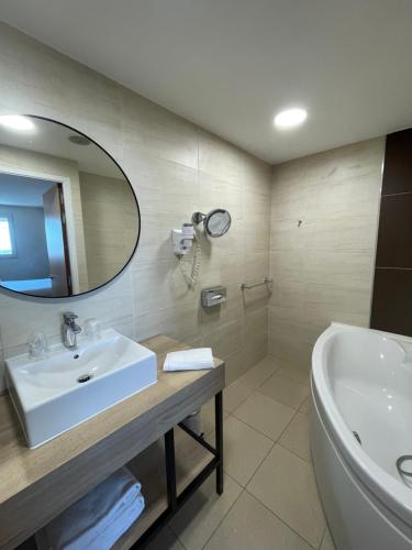 een badkamer met een wastafel, een bad en een spiegel bij Campanile Montpellier Ouest - Croix D'Argent in Montpellier