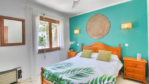 1 dormitorio con cama y pared azul en Residencial Galeretes, en Denia