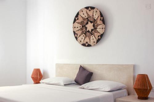 a bedroom with two beds and a clock on the wall at Paje White House Boutique Hotel in Paje