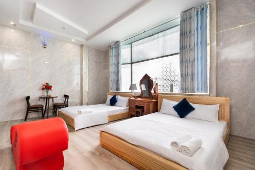 1 dormitorio con 2 camas y silla roja en Khách Sạn Tràng An en Thu Dau Mot