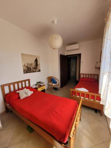 a bedroom with two beds with red sheets at Villa La Pelosa Stintino in Stintino
