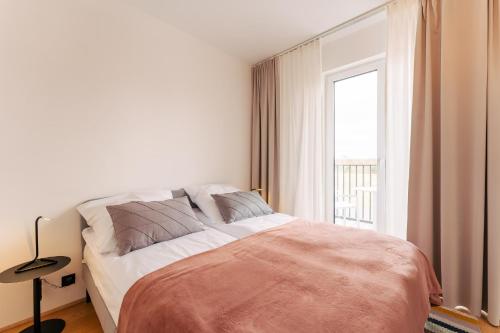 ein weißes Schlafzimmer mit einem Bett und einem Fenster in der Unterkunft Apartament SEASHELL SurfingBird Dźwirzyno in Dźwirzyno