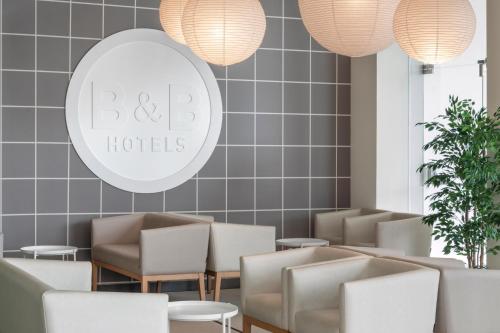 a waiting room at a hotel with chairs and lights at B&B HOTEL Lisboa Aeroporto in Lisbon