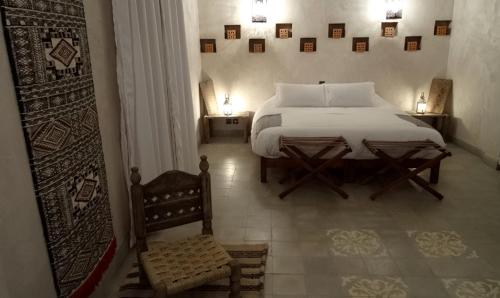 a bedroom with a white bed and a chair at L'Ma Lodge in Skoura