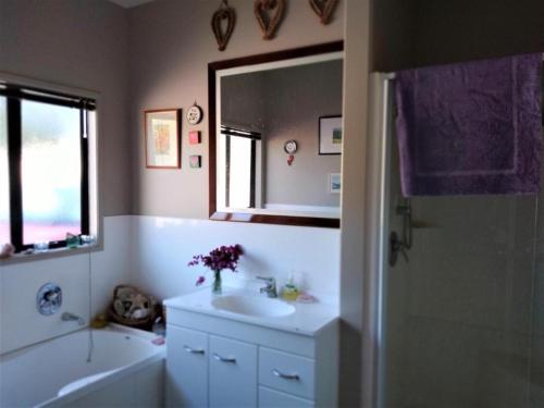 uma casa de banho com um lavatório, uma banheira e um espelho. em U Beauty - B & B em Whangarei