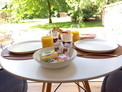 a white table with a bowl of food and glasses of orange juice at B&B Schoonhoven Suites in Elim
